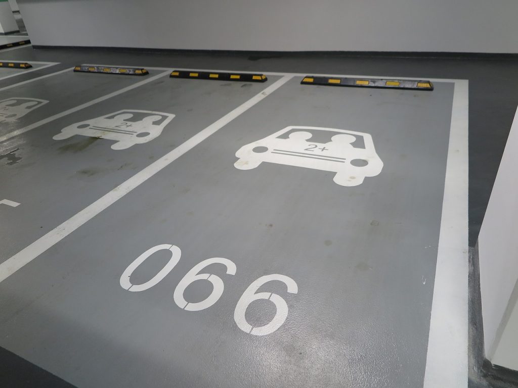 Linemarking and stencils used to regulate user category in a car park. 